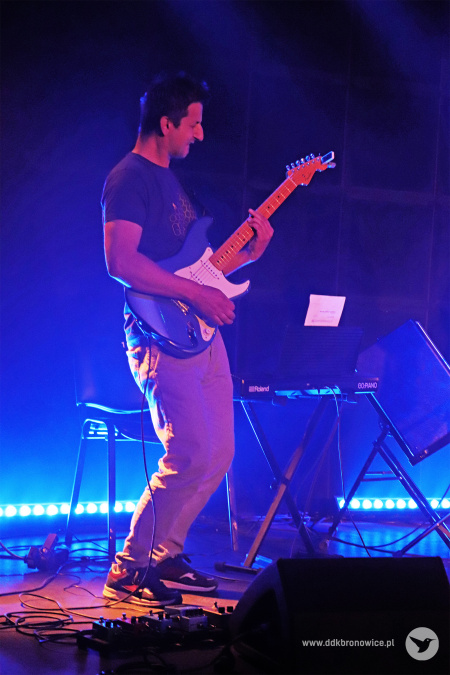 Kolorowe zdjęcie. Mężczyzna na scenie gra na gitarze elektrycznej.