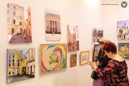 Kolorowe zdjęcie. Dwie kobiety rozmawiają, oglądając wystawę. Na ścianach widać obrazy i zdjęcia Lublina.