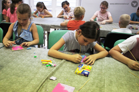 Kolorowe zdjęcie. Dzieci siedzą przy stołach i tworzą monotypie z plasteliny.