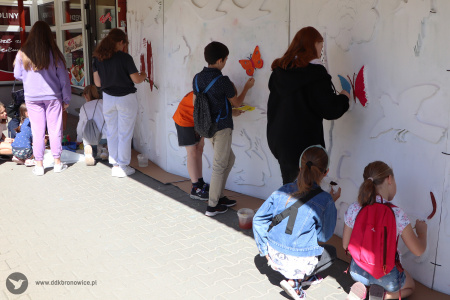 Kolorowe zdjęcie. Dzieci malują farbami na wielkoformatowej ściance z konturami zwierząt.
