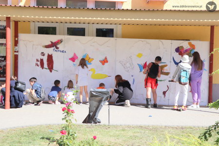 Kolorowe zdjęcie. Dzieci malują farbami wielkoformatową ściankę ze zwierzętami.