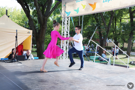 Kolorowe zdjęcie. Dziewczynka z chłopcem tańczy w parze taniec towarzyski na scenie.