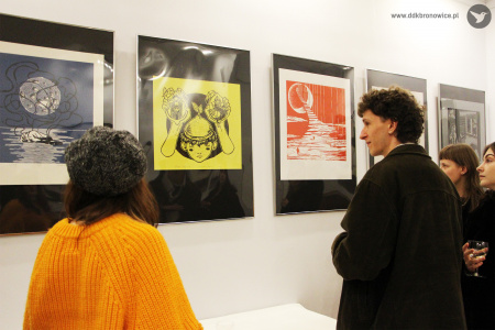 Kolorowe zdjęcie. Trzy osoby oglądają linoryty na wystawie.