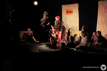zdjęcie kolorowe. Na oświetlonej scenie przebrane dzieci odgrywają przedstawienie.