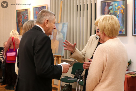 Zdjęcie. Mężczyzna stojący po lewej stronie rozmawia z autorką wystawy oraz inną uczestniczką wystawy.