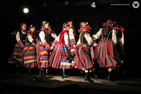 Zdjęcie kolorowe. Grupa dziewczynek w strojach ludowych tańczy na scenie.