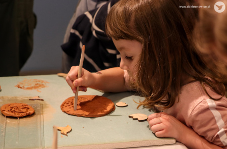 Zdjęcie kolorowe. Dziewczynka nanosi wzory na glinę.