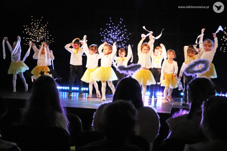 Zdjęcie. Dzieci tańczą na scenie. Mają uniesione wysoko ręce.