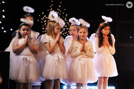 Zdjęcie. Dziewczynki w strojach aniołków stoją ze złożonymi do modlitwy dłońmi.