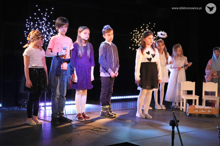 Zdjęcie. Kilkoro dzieci stoi na scenie. Jedna dziewczynka recytuje.