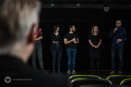 Kolorowe zdjęcie. Na scenie grupa pięciu osób opowiada o projekcie. Kadr zza mężczyzny na widowni.