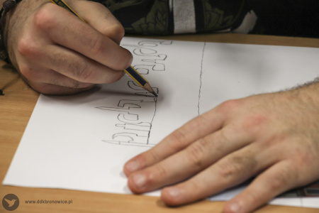 Kolorowe zdjęcie. Męskie dłonie szkicują ołówkiem ornamenty na białej kartce.