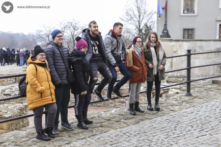 Kolorowe zdjęcie. Grupa osób stoi oparta o barierkę w kurtkach.