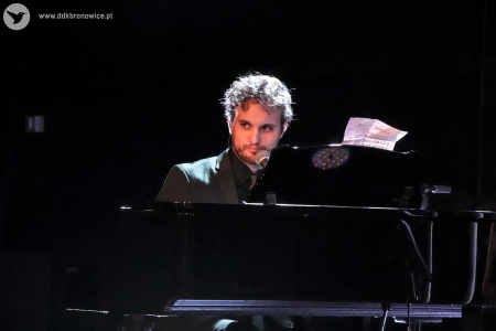 Zdjęcie. Janek Traczyk siedzi za fortepianem.