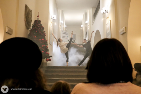Kolorowe zdjęcie. Para tancerzy tańczy choreografię baletową na wewnętrznych schodach Ratusza Lubelskiego. Za nimi dym sceniczny. Kadr zza widowni.