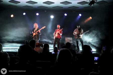 Kolorowe zdjęcie. Na scenie zespół NIEBØ - Aga Ozon, Adrian Kieroński i Piotrek Rudnicki. Wszyscy grają na gitarach. Zdjęcie zza widowni.