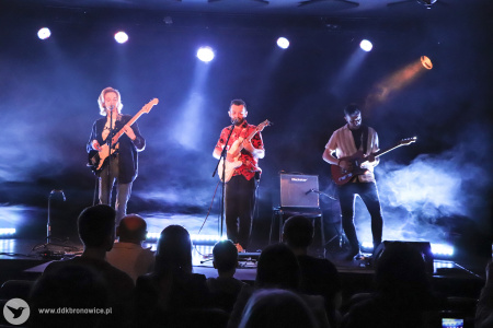 Kolorowe zdjęcie. Na scenie zespół NIEBØ - Aga Ozon, Adrian Kieroński i Piotrek Rudnicki. Wszyscy grają na gitarach. Aga i Adrian śpiewają. Zdjęcie zza widowni.