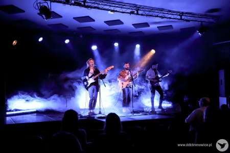 Kolorowe zdjęcie. Na scenie zespół NIEBØ - Aga Ozon, Adrian Kieroński i Piotrek Rudnicki. Wszyscy grają na gitarach. Aga i Adrian śpiewają.