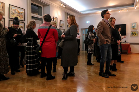 Kolorowe zdjęcie. Kilka osób ogląda akwarele Wiesława Stefańskiego. Grupka osób rozmawia ze sobą.