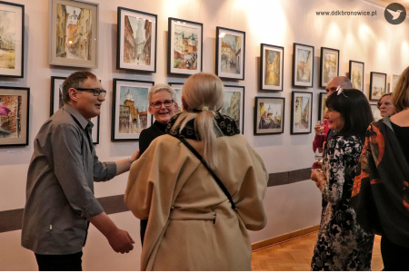 Kolorowe zdjęcie. Wiesław Stefański rozmawia z dwiema kobietami. W tle obrazy na ścianach Galerii.