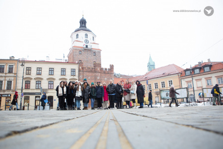 Kolorowe zdjęcie. Uczestnicy warsztatów pozują na tle Bramy Krakowskiej w grupie.