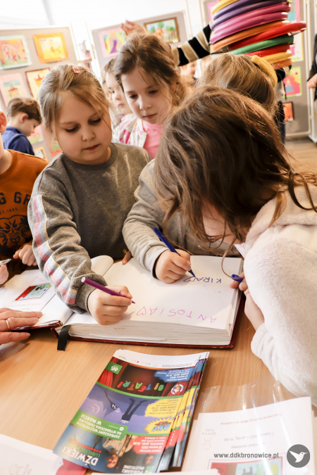 Grupa dzieci wpisuje się do księgi pamiątkowej.