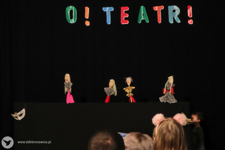 Kolorowe zdjęcie. Czarna zasłona z napisem O! Teatr! Przed zasłoną widać cztery laleczki kukiełkowe wykonane na warsztatach.