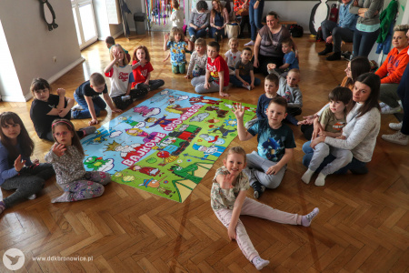Kolorowe zdjęcie. Dzieci siedzą na podłodze wokół ułożonego z puzzli obrazka z napisem Bajkowe Opowieści.