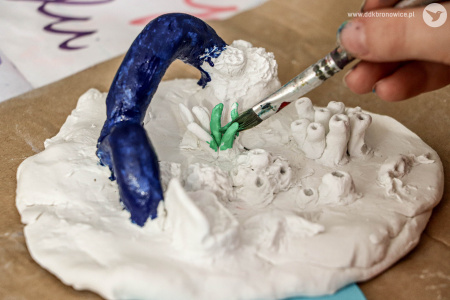 Makieta rafy koralowej. Chłopiec pomalował fragment na niebiesko. Teraz maluje na zielono.