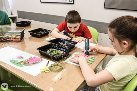 Chłopiec i dziewczynka kolorują specjalnymi urządzeniami kolorowanki.