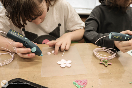 Dziewczynki kolorują kwiatuszki. używają do tego specjalnego kleju na gorąco.