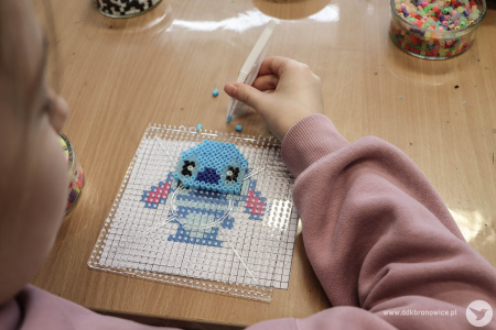 Dziewczynka układa koraliki. Stworzyła Stitcha - niebieskiego stworka z animacji.