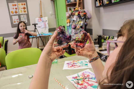 Sala warsztatowa. Dziewczynka pokazuje dwa złączone serca. Są pokolorowane.