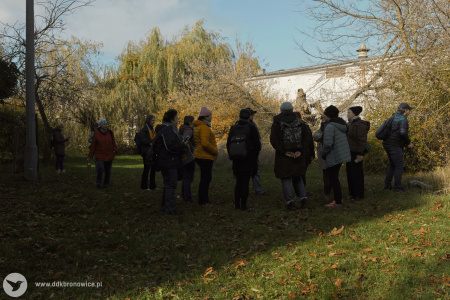 Uczestnicy rozmawiają w kole na dworze. Widać drzewa, trawę i krzewy.