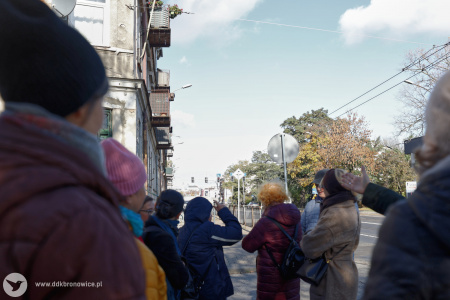 Na pierwszym planie uczestnicy plenerowych warsztatów. W tle ruchliwa ulica, sygnalizacja świetlna i po lewej stronie kamienica.