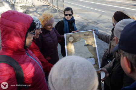 Uczestnicy oglądają mapę historyczną na chodniku.