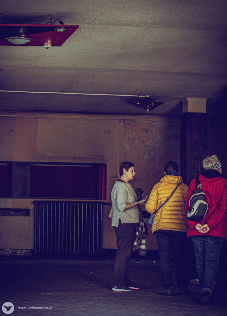 Ciemna i brudna sala. po prawej stronie widać dwie kobiety. Jedna z nich to przewodniczka.