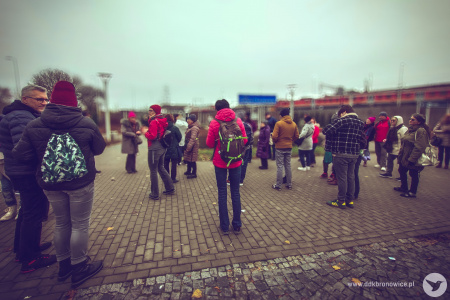 Uczestnicy spaceru z przewodnikiem. Pochmurno. W tle widać pociąg i dworzec PKP w Lublinie.