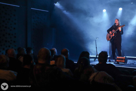Jasne światło za artystą. Muzyk z przodu oświetlony jest żółtym światłem.