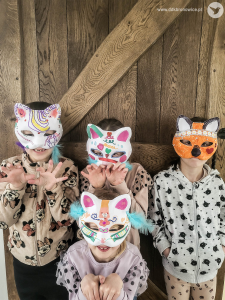 Cztery dziewczynki pozują do zdjęcia. Na głowach mają kolorowe maski kotów. Ubrane są w bluzy z kocimi motywami.