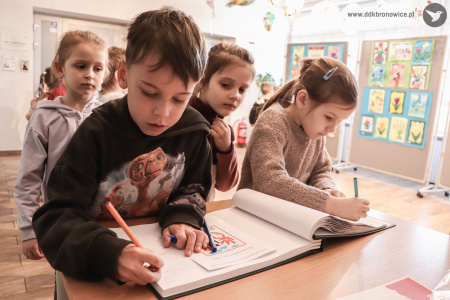 Wpisy do księgo gości Galerii Małej. Chłopiec i dziewczynka wpisują się. Za nimi kolejka dzieci.