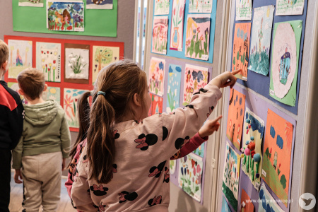 Dwie dziewczynki pokazują sobie obrazy. Wskazują na nie palcami.