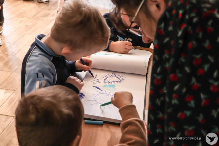 Dzieci wpisują się do księgi gości. Podpisują się i rysują słoneczka.