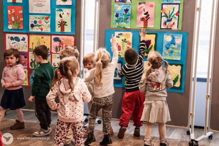 Dzieci stają na palce, żeby wskazać swoje obrazy.