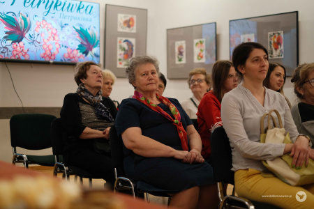 Kobiety, autorki siedzą na krzesłach, na środku Galerii Krańcowej. W tle widać na telewizorze logo grupy.