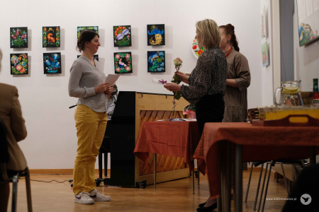 Autorka w żółtych spodniach i jasnej koszuli odbiera kwiaty i dyplom z rąk Ewy Rejmak i Oleny Kovalenko.