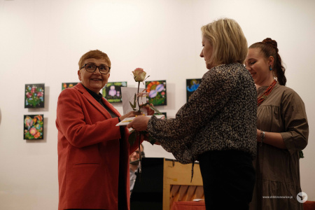 Ewa Rejmak i Olena Kovalenko rozdają dyplomy i kwiaty. Podziękowania odbiera starsza kobieta ubrana w czerwony żakiet.