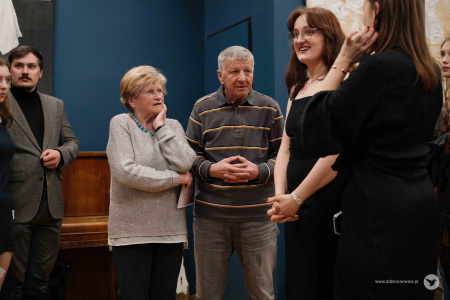 Po prawej stronie autorka części obrazów. Po lewej stronie słuchająca zebrana publiczność. W środku stoi starsza kobieta i starszy mężczyzna.