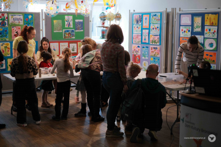 Pracownie Kultury Maki. W korytarzy rozłożony stół. Za stołem widać w żółtej koszulce Olene Kovalenko. Wokół stołu dzieci.