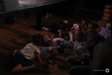 Dzieci leża na podłodze. Widać unoszące się bańki mydlane.